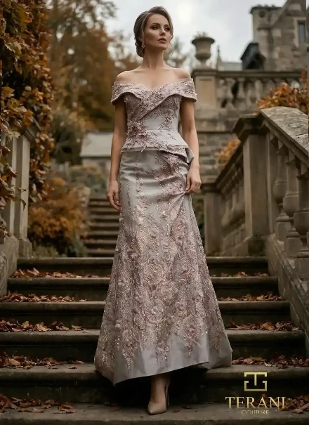 Model wearing a silver and blush Terani Couture off-the-shoulder formal gown with intricate embroidery and floral appliqués.